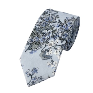 May include: A light blue necktie with a floral pattern in shades of blue and grey.
