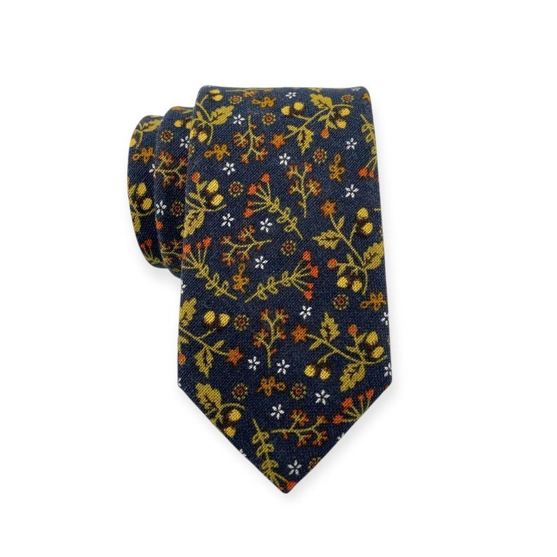 May include: A navy blue necktie with a repeating floral pattern in shades of gold, orange, and white. The tie is knotted and displayed against a white background. The floral design includes small flowers and leaves.