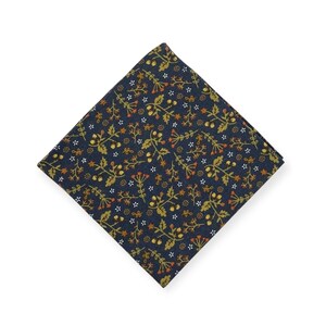 May include: A navy blue pocket square with a repeating floral pattern in gold, orange, and white. The square is folded in a diamond shape, showcasing the detailed botanical design. This accessory is suitable for formal or casual wear.