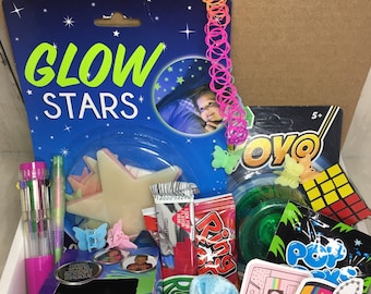 May include: A box filled with various toys and trinkets, including a glow-in-the-dark star, a yo-yo, a slinky, a ring pop, a pack of candy, a scrunchie, a cassette tape, a Tamagotchi, and a pack of colorful pens.