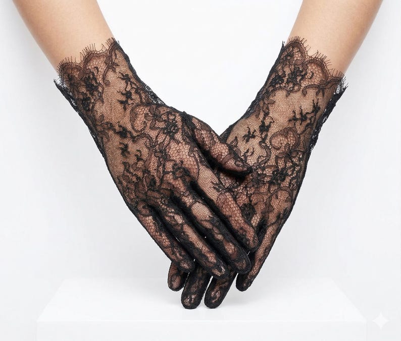 May include: Black lace gloves with intricate floral patterns. The gloves have a delicate, scalloped edge at the wrist. The sheer fabric allows the skin to be visible, creating an elegant and romantic look.