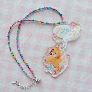 May include: A colourful beaded necklace with a clear acrylic charm featuring a cartoon Shiba Inu dog with the Japanese text "大" and a speech bubble with the Japanese text "フフフ!"