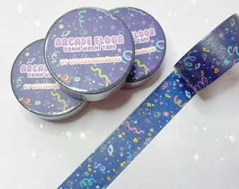 May include: Three rolls of blue washi tape with a gold glitter finish. The tape features a repeating pattern of confetti, planets, and streamers. The tape is labeled "Arcade Floor 20mm Washi Tape by LittlePinkGoblin".