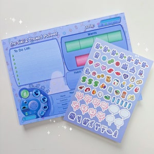 May include: A blue and white planner with 'The Sims 2 Themed Planner' printed on the front. The planner has a to-do list, wants, habits, and mood sections. There are also stickers with various Sims 2 icons, including hearts, smiley faces, and houses.