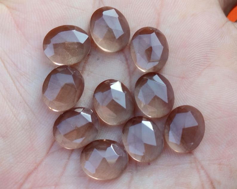 May include: Ten faceted, translucent, light brown gemstones. The stones are oval shaped and have a smooth, polished finish.