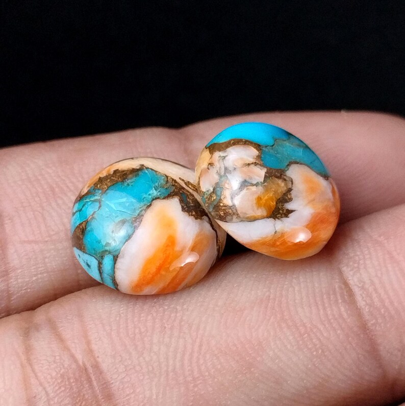 May include: Two round, smooth, turquoise cabochons with brown and orange veins. The stones have a mottled, marbled appearance.