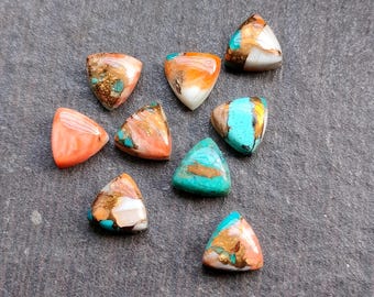 Op de afbeelding: Tien driehoekige edelsteencabochons in verschillende tinten oranje, roze, turquoise en bruin. De stenen zijn in een driehoekige vorm gezet en hebben een gepolijste afwerking.