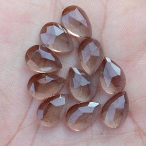 Pu&ograve; includere: Una collezione di dieci perle di pietra preziosa sfaccettate a forma di goccia di colore marrone chiaro. Le perle sono traslucide e hanno un leggero luccichio.