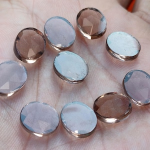 May include: Ten oval-shaped, faceted, smoky quartz gemstones. The stones are translucent and have a light brown color.