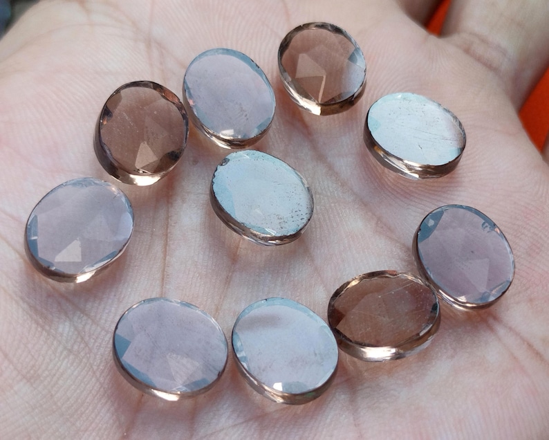 May include: Ten oval-shaped, faceted, smoky quartz gemstones. The stones are translucent and have a light brown color.