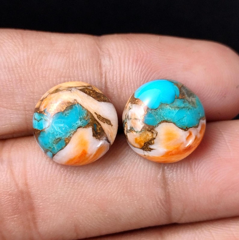 May include: Two round turquoise cabochons with copper and white accents. The stones have a marbled pattern of blue, white, orange, and copper.
