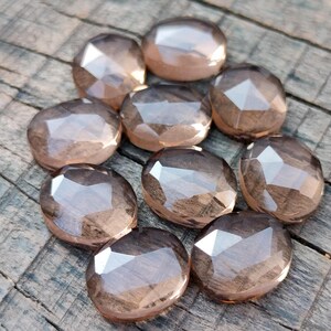 May include: Ten faceted smoky quartz gemstones in various sizes and shapes. The stones are a light brown color and have a translucent appearance.