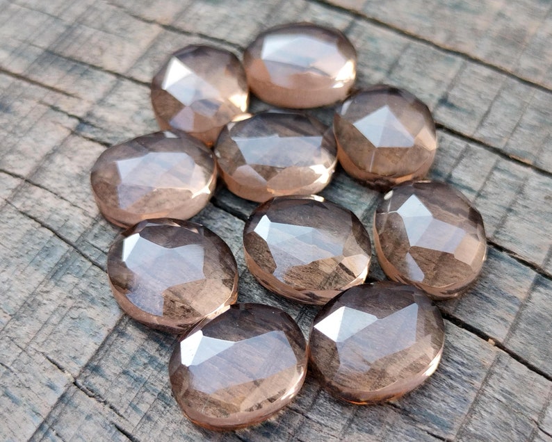 May include: Ten faceted smoky quartz gemstones in various sizes and shapes. The stones are a light brown color and have a translucent appearance.