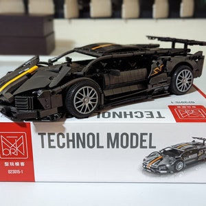 Könnte beinhalten: Ein schwarzes und gelbes Sportwagen-Modellbausatz mit dem Text "TECHNOL MODEL" auf der Schachtel. Die Schachtel zeigt auch ein Bild des Autos.