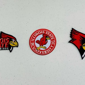 Peut inclure: Trois patchs brodés représentant le logo de l'Université de l'État de l'Illinois. Le premier patch montre les mots "Illinois State Redbirds" avec une tête de cardinal rouge. Le deuxième patch est un patch circulaire avec les mots "Illinois State University" et un cardinal rouge. Le troisième patch est une tête de cardinal rouge.
