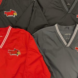 May include: Four windbreaker jackets in black, red, and gray with a white v-neck and white trim. Each jacket has an embroidered logo that says "Illinois State Redbirds" with a red cardinal bird.