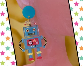May include: A pair of blue robot earrings with a turquoise background. The robot has a red mouth, yellow eyes, and a white and black control panel.