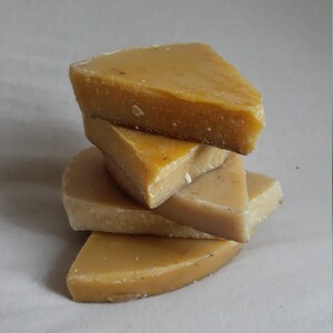 May include: A stack of four yellow beeswax blocks, each shaped like a triangle with rounded edges.