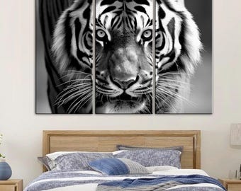 May include: Black and white tiger art print set. The artwork is divided into three panels, showcasing a close-up of a tiger's face. The tiger's fur is detailed, and its eyes are focused. The art is displayed above a wooden bed frame.
