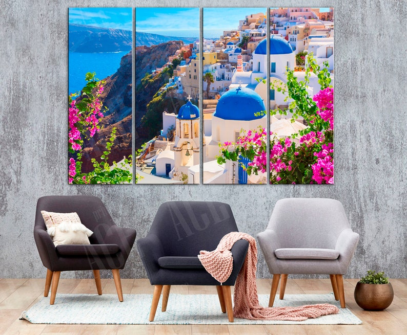 May include: A three-panel canvas print depicting a picturesque view of a white-washed village with blue domed buildings, nestled on a cliff overlooking a turquoise sea. Lush greenery and vibrant pink flowers add a touch of color to the scene.