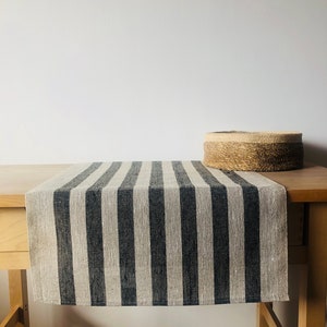 Könnte beinhalten: Ein schwarz-weiß gestreifter Tischläufer aus Leinen auf einem Holztisch. Der Tischläufer ist etwa 35 cm breit und 178 cm lang.