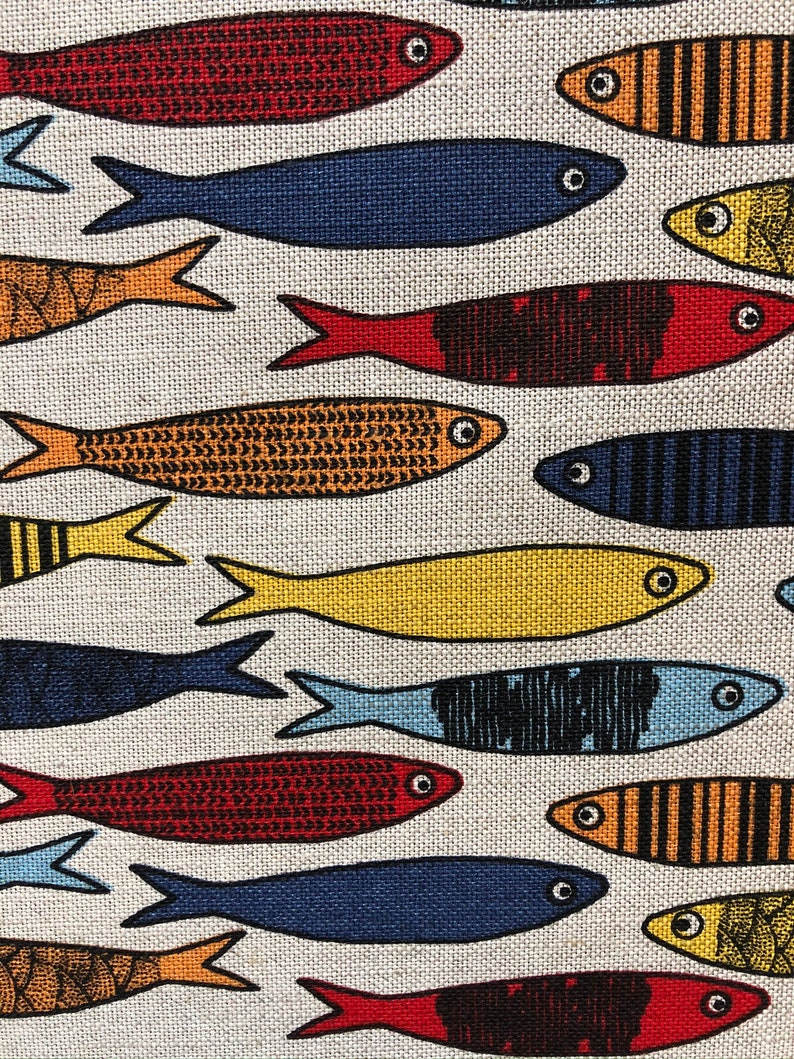 May include: A white fabric with a repeating pattern of colorful fish. The fish are in various shades of red, orange, yellow, blue, and black. The fish are stylized and have a simple design.