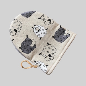 以下が含まれることがあります： 黒と白の羊の模様がついた、ベージュのリネン製の巾着袋。袋には茶色のロープの取っ手があります。