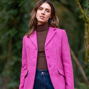 May include: A pink tweed blazer with a brown turtleneck sweater underneath. The blazer has a single-breasted closure with four buttons and flap pockets.