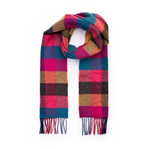 Könnte beinhalten: Ein bunter karierter Schal mit Fransen an den Enden. Der Schal ist aus einem weichen, warmen Stoff gefertigt und hat eine Mischung aus rosa, blauen, braunen und gelben Farbtönen.