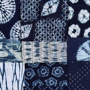 May include: A patchwork of indigo-dyed fabric squares with various white patterns. Designs include spiral, geometric, and floral motifs. The fabric has a textured appearance, showcasing the traditional tie-dye technique.