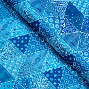 Op de afbeelding: Close-up van een stof met een patchwork-ontwerp in blauwtinten. De stof is verdeeld in driehoekige secties, elk met een ander patroon, waaronder paisley en geometrische motieven. Het algehele effect is een levendig, gestructureerd oppervlak.