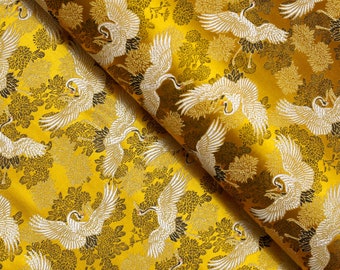 May include: A gold fabric with a repeating pattern of white cranes flying in a yellow and black floral design.