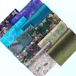 May include: A collection of rectangular fabric swatches arranged in a diagonal pattern. The textiles feature diverse designs including floral motifs, intricate paisley patterns, and solid satin finishes in shades of purple, teal, green, and gold.