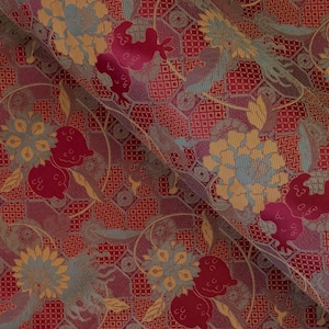 May include: Red fabric with a repeating pattern of flowers, leaves, and geometric shapes in shades of gold, brown, and blue.