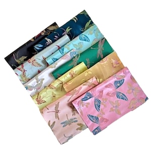 Könnte beinhalten: Eine Sammlung von zehn Stoffproben mit Libellen- oder Schmetterlingsmotiven. Die Stoffe sind in verschiedenen Farben, darunter Pink, Grün, Blau und Gelb. Der Stoff ist ein Brokat mit Satin-Finish.