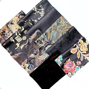 May include: A collection of fabric swatches featuring black backgrounds with diverse patterns including white cherry blossoms, gold calligraphy, intricate paisley, tonal floral textures, and vibrant multi-colored floral prints.