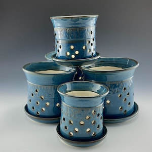 Peut inclure: Présentation de cinq bougeoirs en céramique bleus. Chaque bougeoir, de forme cylindrique, est percé de trous circulaires et accompagné d'une soucoupe assortie. Les bougeoirs présentent une finition brillante et une bande texturée au centre.