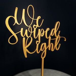 May include: Gold-coloured wooden cake topper with the text "We Swiped Right" in a cursive font.