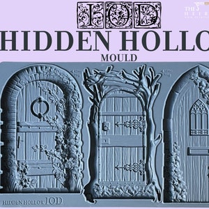 May include: A silicone mold for making three different decorative door designs. The mold is gray and features a detailed design of a wooden door with vines and a stone archway. The mold is labeled "HIDDEN HOLLOW IOD MOULD".