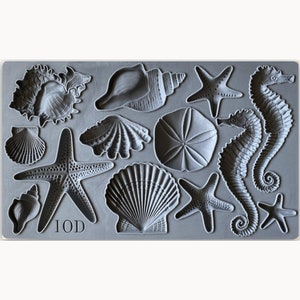 May include: A gray silicone mold with 12 different sea-themed designs, including seashells, starfish, and seahorses. The mold is labeled "IOD".