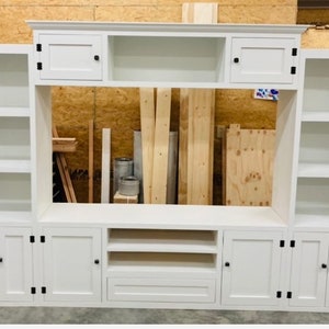 May include: White entertainment unit with a built-in shelf, two cupboards, and a drawer. The unit has a white painted finish and black hardware.