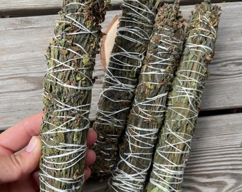 Può includere: Quattro mazzi di erbe secche legate con spago bianco. I mazzi sono verdi e marroni e hanno un aspetto naturale e rustico.