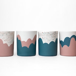 May include: Four ceramic cups with a white base, a pink and teal design, and a speckled glaze.