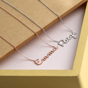 May include: Three delicate necklaces with personalized names, "Emma", "Paige", and a third name, displayed on a brown and yellow background.