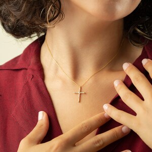 May include: A gold chain necklace with a small, diamond-encrusted cross pendant.