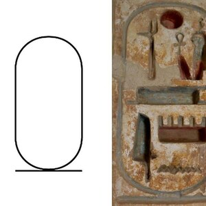 May include: A white and brown rectangular stone with a carved image of an Egyptian hieroglyphic cartouche. The cartouche is surrounded by a decorative border and contains a series of symbols, including a sun disk, a staff, and a serpent.