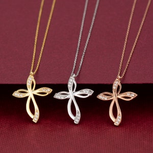 May include: Three delicate necklaces with a diamond-encrusted infinity cross pendant. The necklaces are available in gold, silver, and rose gold.