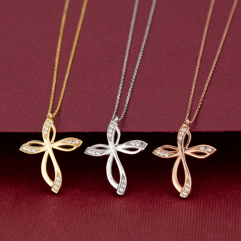 May include: Three delicate necklaces with a diamond-encrusted infinity cross pendant. The necklaces are available in gold, silver, and rose gold.