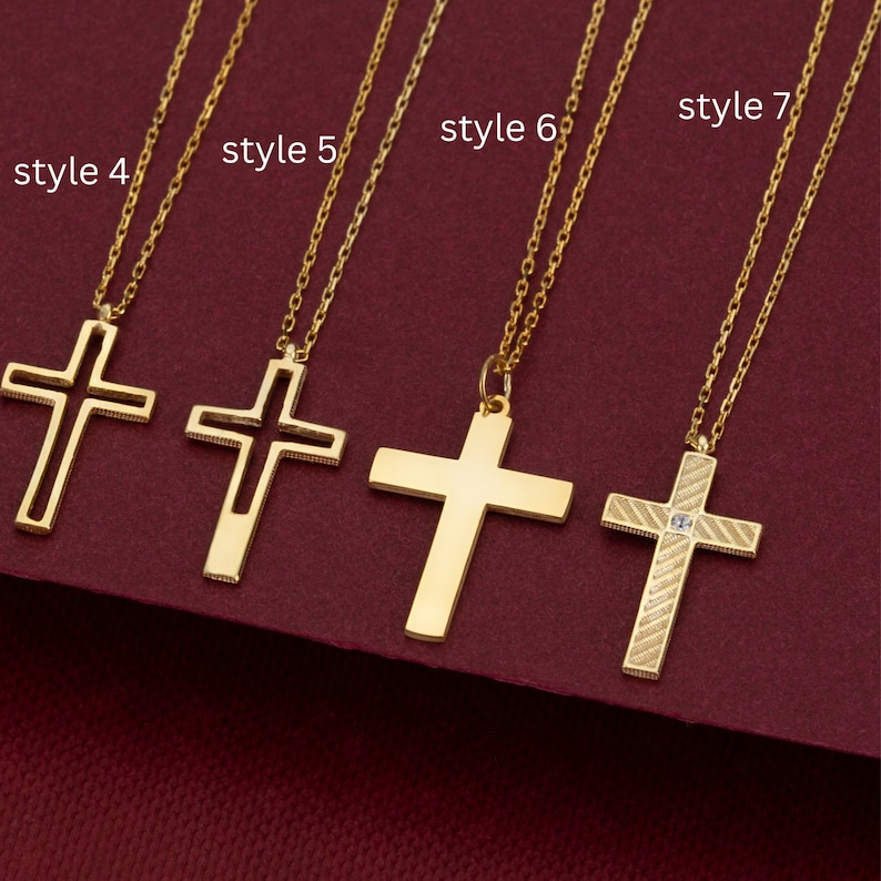 May include: Five gold cross necklaces with different styles. The crosses are all different shapes and sizes. The necklaces are all on a red background.