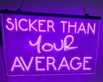 May include: A rectangular, purple neon sign with the words "SICKER THAN your AVERAGE" in white, illuminated lettering. The sign is suspended by a chain and has a black border. A power cord extends from the left side.